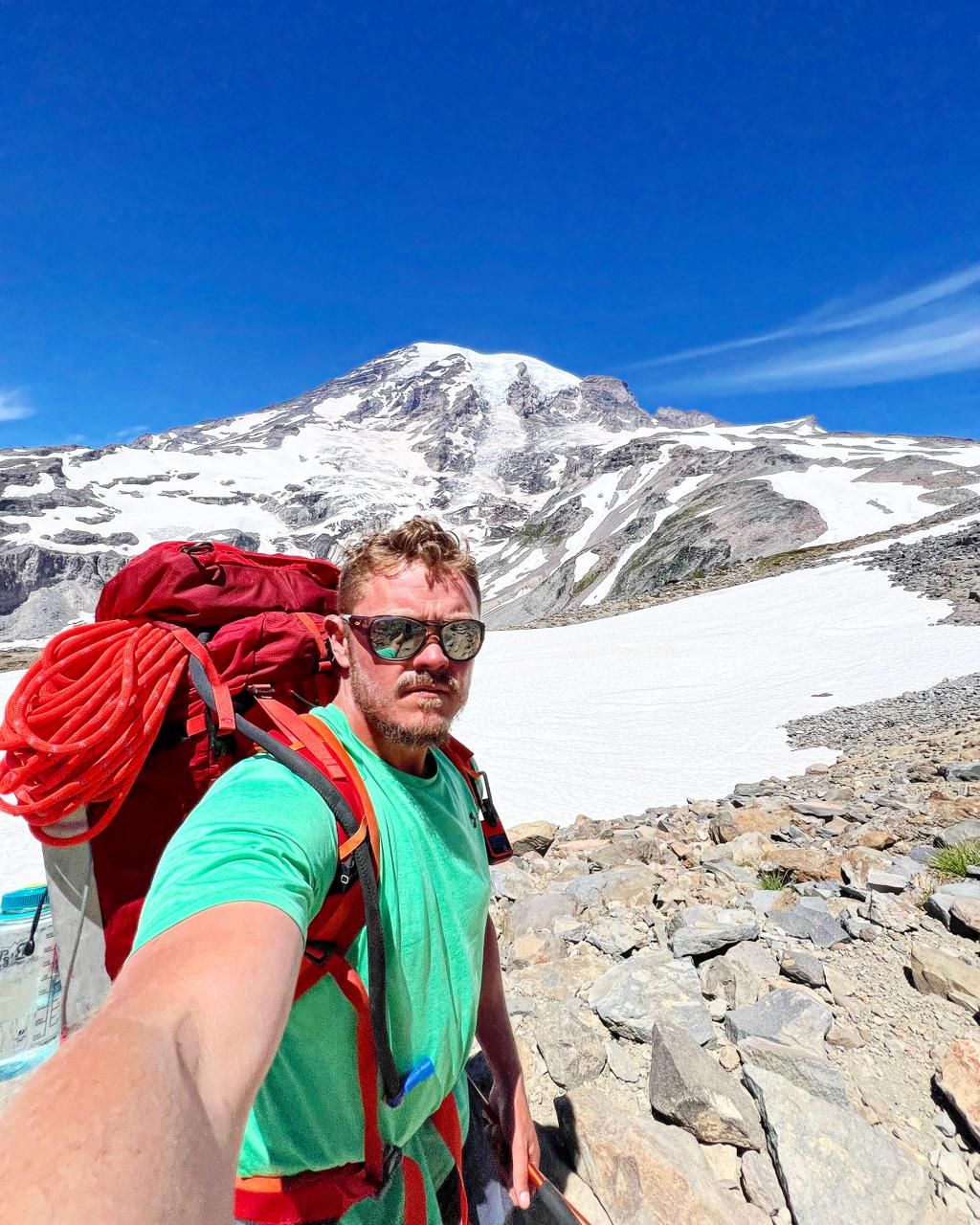 Trenton with a climbing pack below Mount Rainier